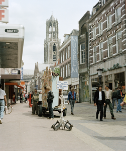 118975 Gezicht in de Steenweg te Utrecht met op de voorgrond een draaiorgel en op de achtergrond de Domtoren.